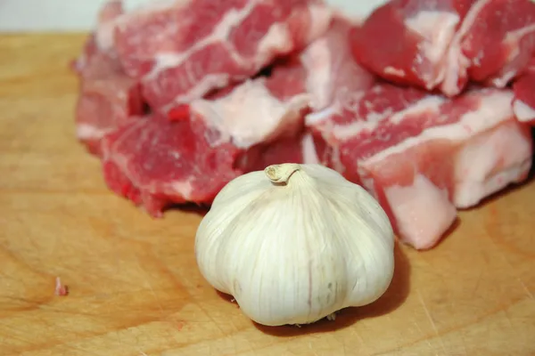 Carne fresca e alho fresco deitado na mesa da cozinha — Fotografia de Stock