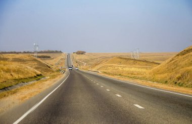 Yol ve hareket halindeki arabalar ve mavi gökyüzü karşı şeritte ilerliyor.