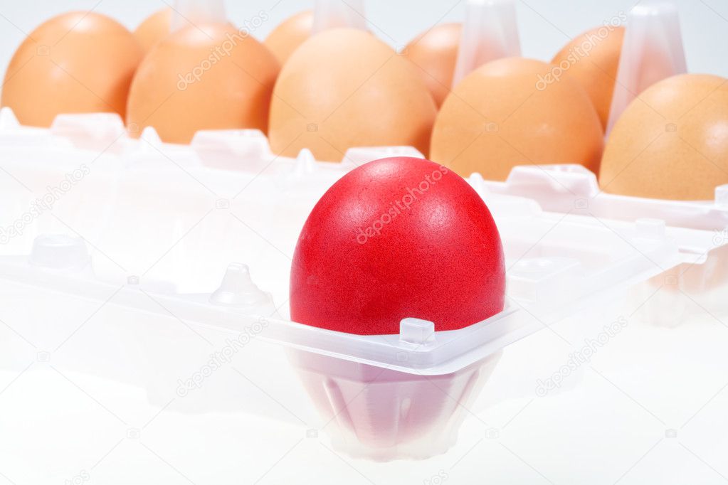 Red chicken egg against several brown eggs