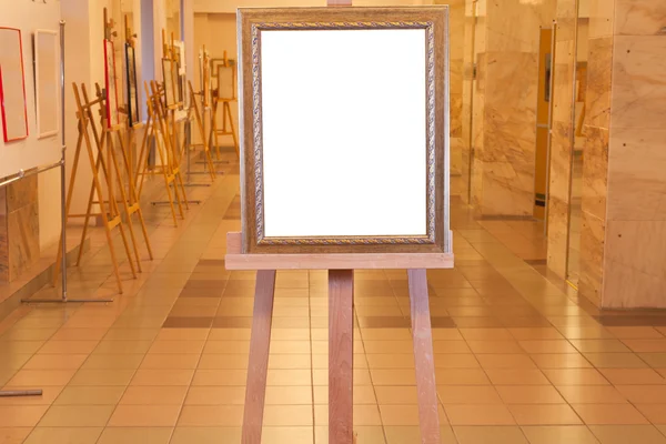 Wooden picture frame on easel in art gallery — Stock Photo, Image