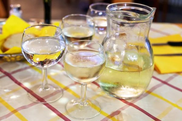 Jarra de vidrio con vino blanco local y copas —  Fotos de Stock