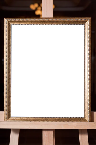 Wooden gold picture frame on easel — Stock Photo, Image