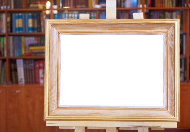 ahşap fotoğraf çerçevesi kitaplığındaki şövale üzerinde beyaz canvas