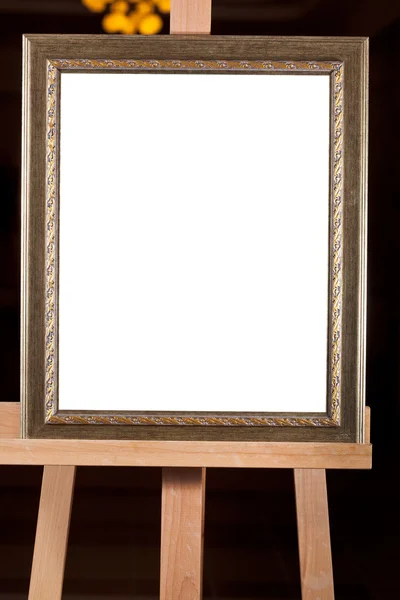 Old picture frame with white cut out canvas on easel — Stock Photo, Image