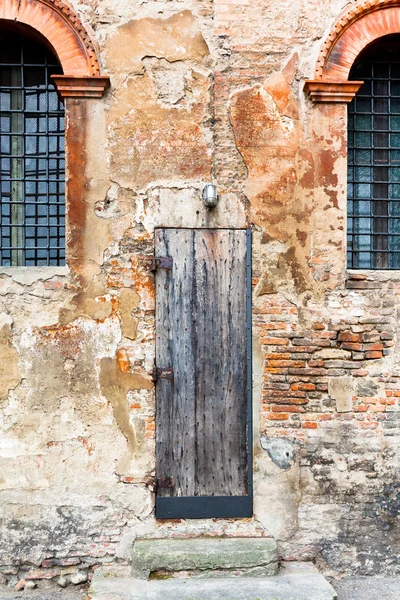 Деревянная дверь в обветшалой кирпичной стене — стоковое фото