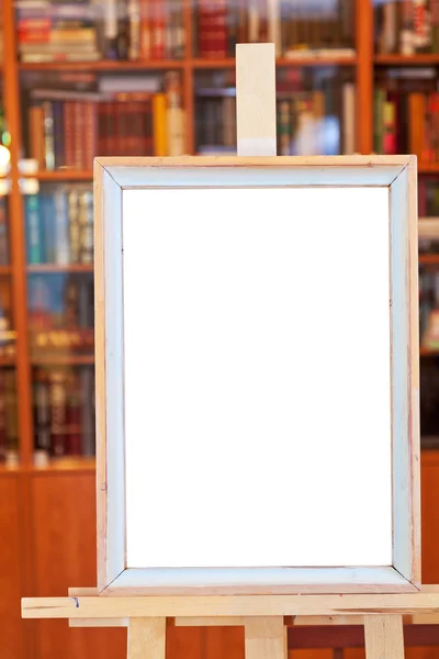 White canvas of simple picture frame on easel in library — Stock Photo, Image