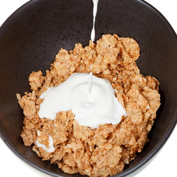 Yoghurt is poured into bowl of cereal — Stock Photo, Image