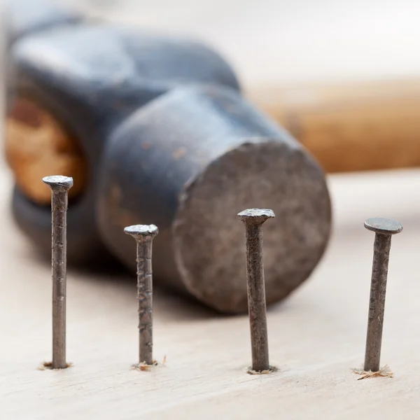 Hammer and nails into wooden plank — Stock Photo, Image