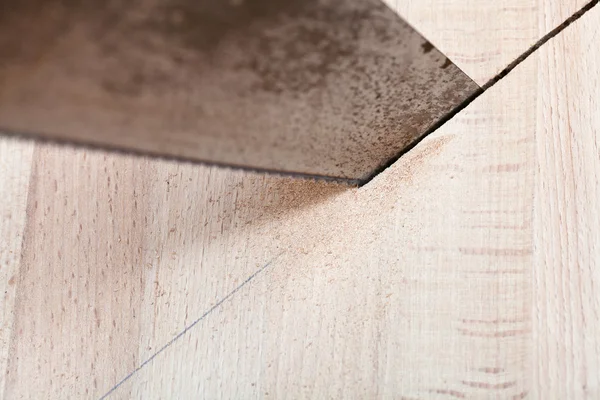 Holzbrett wird mit der Hacksäge zugeschnitten — Stockfoto