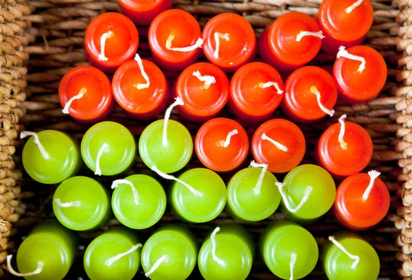 Velas vermelhas e verdes na cesta tecida — Fotografia de Stock