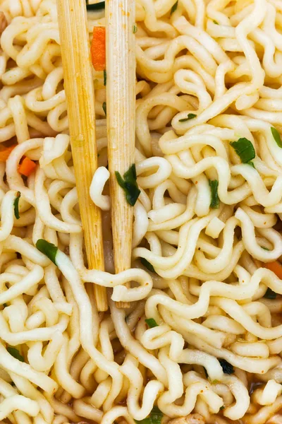 Wooden chopsticks on cooked instant noodles — Stock Photo, Image