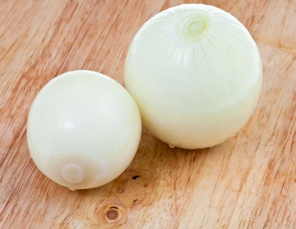 Dos cebollas peladas frescas sobre tabla de madera — Foto de Stock