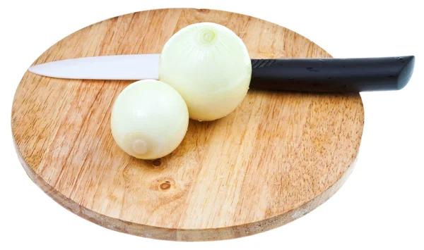 Bulbos de cebolla con cuchillo de cerámica en la tabla de cortar — Foto de Stock