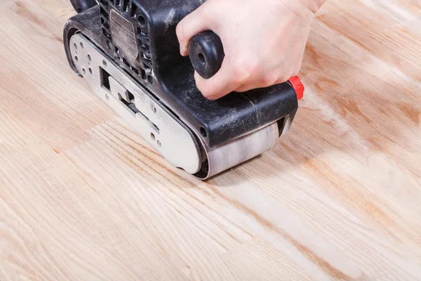 Finishing wooden surface by hand-held belt sander — Stock Photo, Image