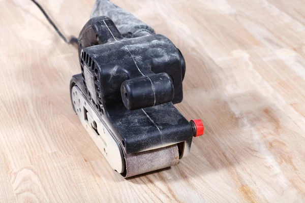 Hand-held belt sander sanding wooden surface — Stock Photo, Image