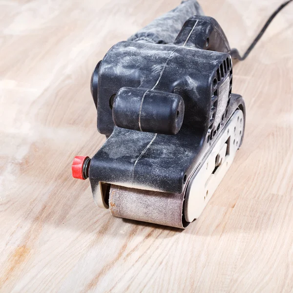 Hand-held belt sander finishing wooden surface — Stock Image Hand-held belt sander finishing wooden surface Stock Photo