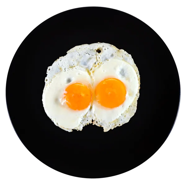 Vista superior de dos huevos fritos en plato negro de cerámica — Foto de Stock