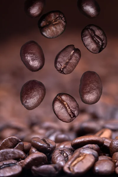 Gebrande koffiebonen vallen op koffie achtergrond — Stockfoto
