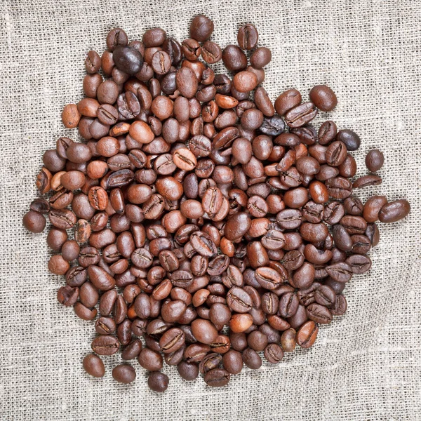 Handful of roasted coffee beans on textile — Stock Photo, Image