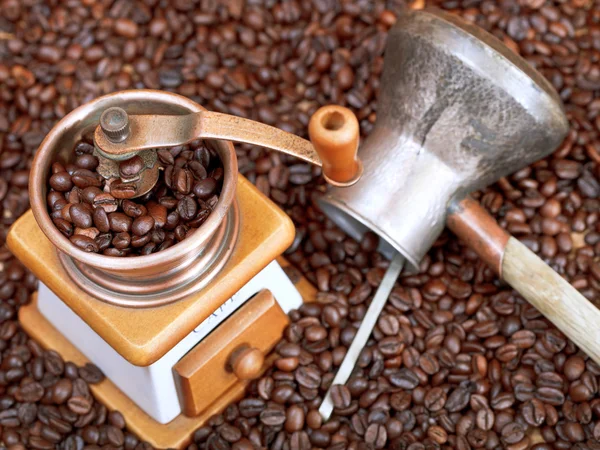 Coffee grinder and copper pot on roasted beans — Stock Photo, Image