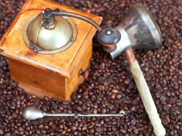 Coffee grinder and copper pot on roasted beans — Stock Photo, Image