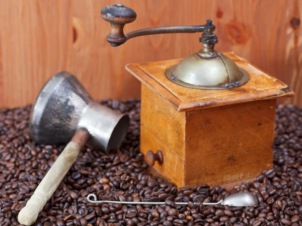 Coffee grinder and copper pot on roasted beans — Stock Photo, Image