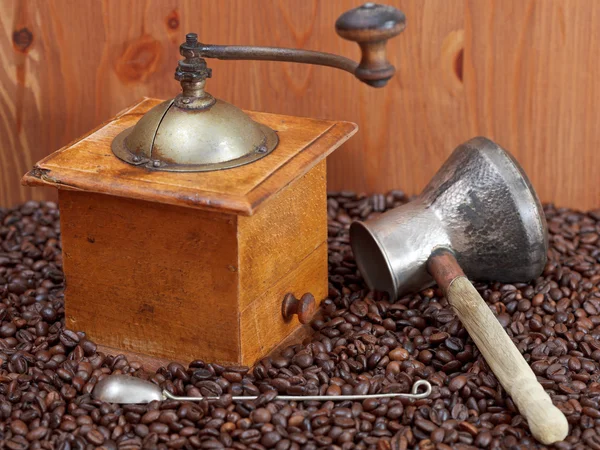 Coffee grinder and copper pot on roasted beans — Stock Photo, Image