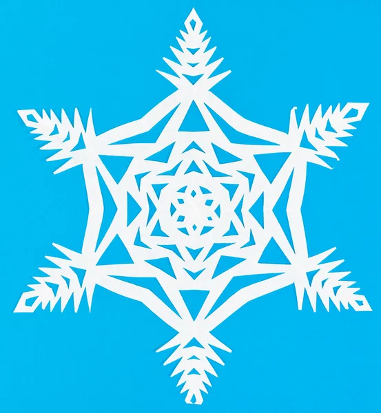 Белый снежинка на голубой бумаге — стоковое фото