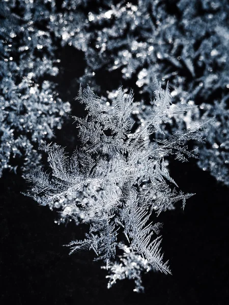 Snowflakes and frost pattern on glass close up — Stock Photo, Image