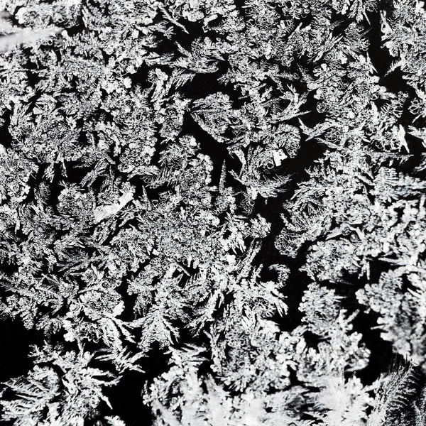 Schneeflocken und Frostmuster auf Glas in Nahaufnahme — Stockfoto