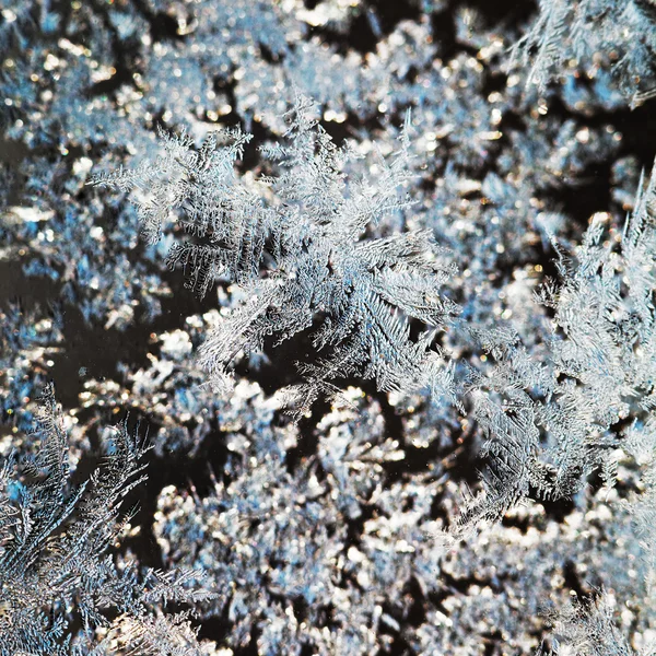 Flocos de neve e padrão de geada em vidro de perto — Fotografia de Stock