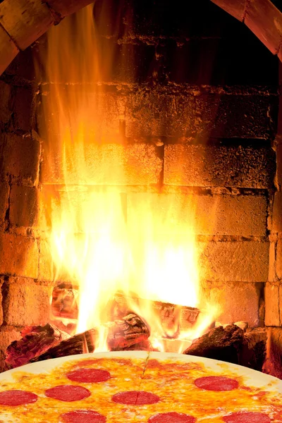 Pizza con salami y llamas de fuego en el horno — Foto de Stock