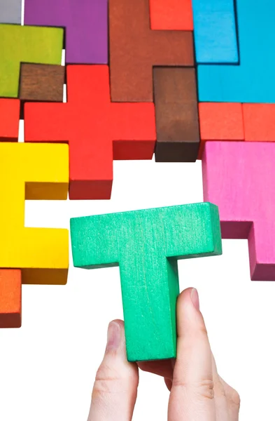 Putting T-shaped block in multicoloured puzzle — Stock Photo, Image