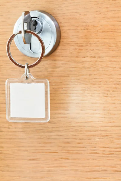 Llave casera con llavero cuadrado en blanco en cerradura — Foto de Stock