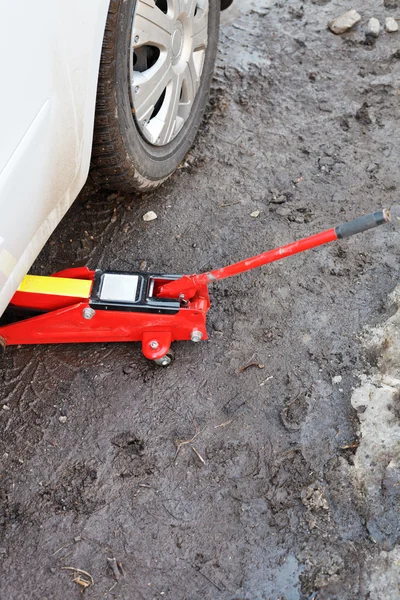 Levantando carro pelo macaco vermelho ao ar livre — Fotografia de Stock