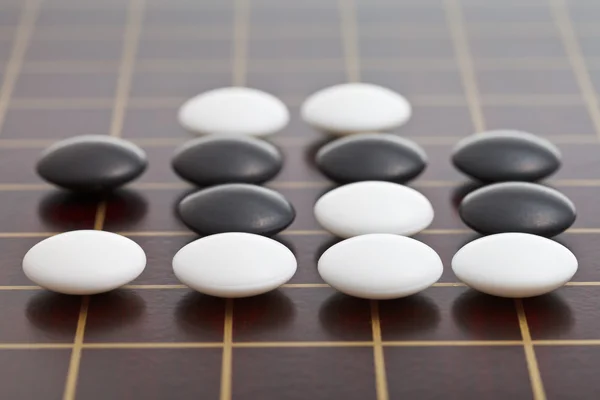 Stones during go game playing on wooden board — Stock Photo, Image