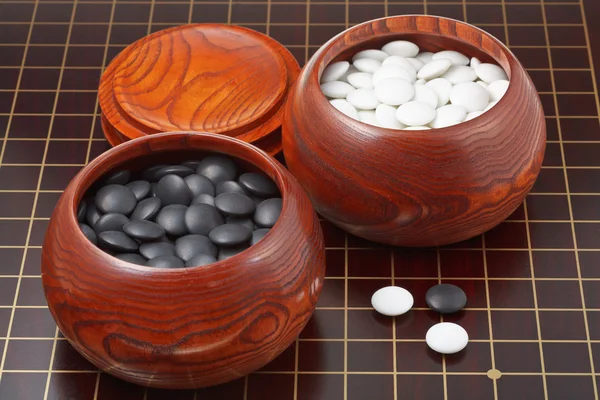 Andare pietre da gioco e ciotole di legno su tavola di legno — Foto Stock