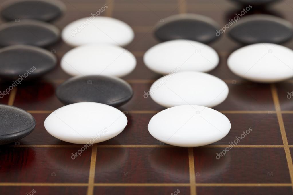 stones during go game playing on wooden desk