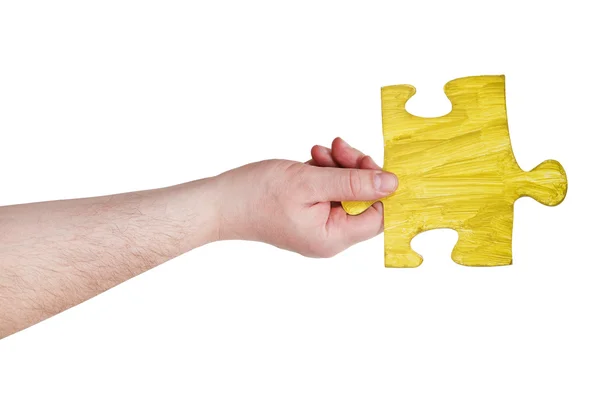 Mão masculina com peça de quebra-cabeça amarelo pintado — Fotografia de Stock