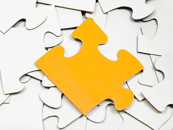 Een gele stuk op stapel voor witte jigsaw puzzles — Stockfoto