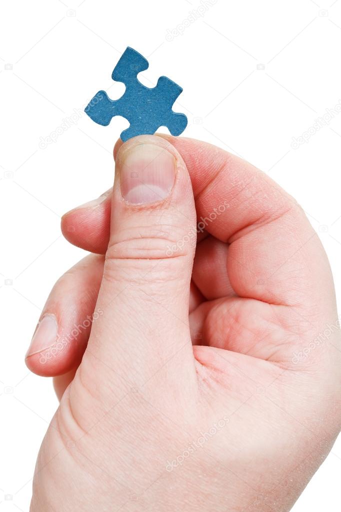 male fingers holding jigsaw puzzle piece