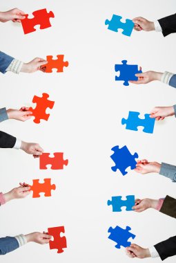 insanlar ellerinde kırmızı ve mavi puzzle parçaları