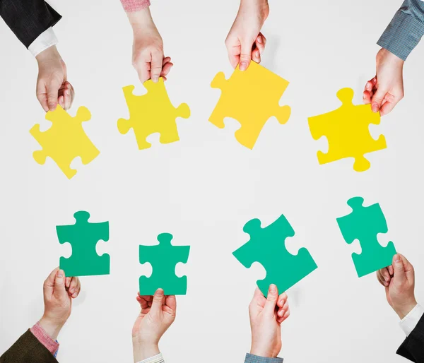Zöld és sárga puzzle darabkái emberek kezében — Stock Fotó