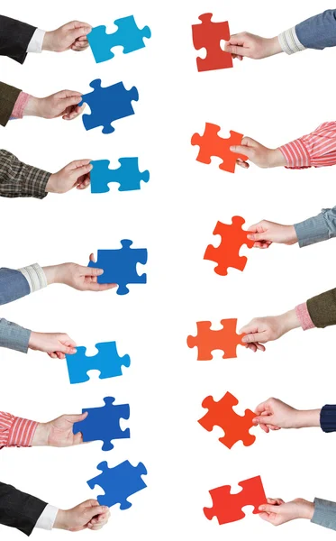 Red and blue puzzle pieces in people hands — Stock Photo, Image