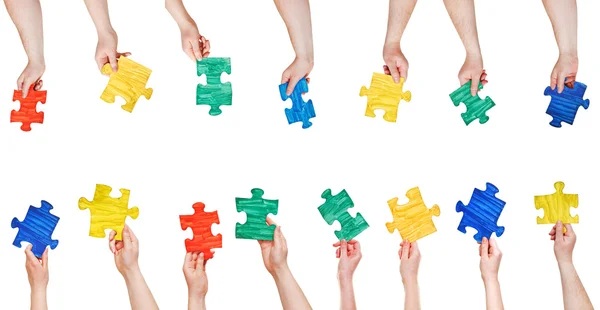 Set of painted puzzle pieces in people hands — Stock Photo, Image