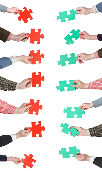 Red and green puzzle pieces in people hands — Stock Photo, Image