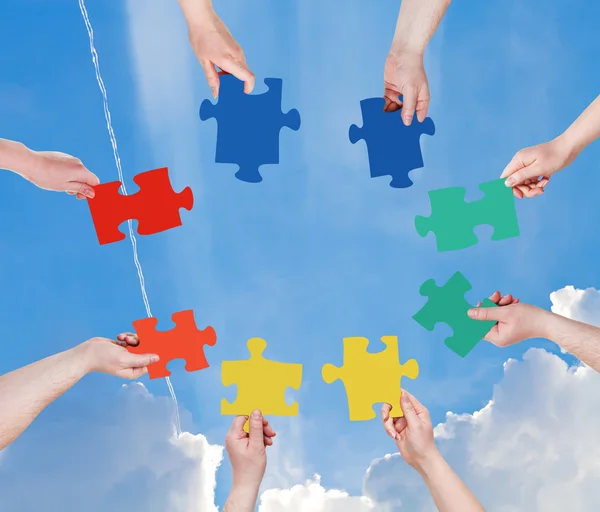 Persone mani con pezzi di puzzle con cielo blu — Foto Stock