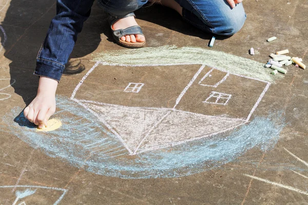 Flicka ritar ett hus med kritor på trottoaren — Stockfoto