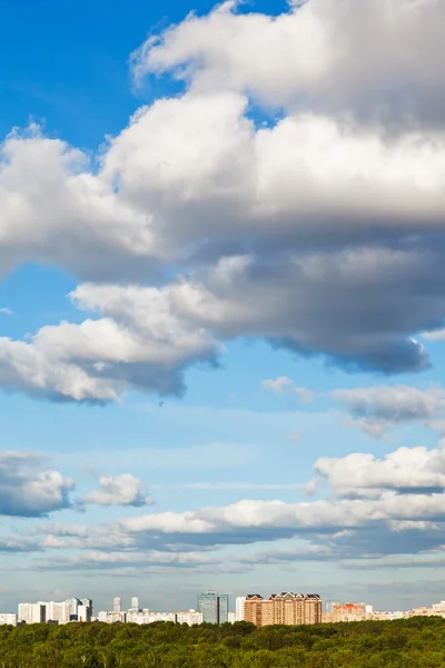 Mavi gökyüzünde büyük beyaz bulutlar altında şehir — Stok fotoğraf