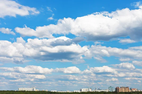 Cityscape with white fluffy clouds in blue sky — Stock Photo, Image